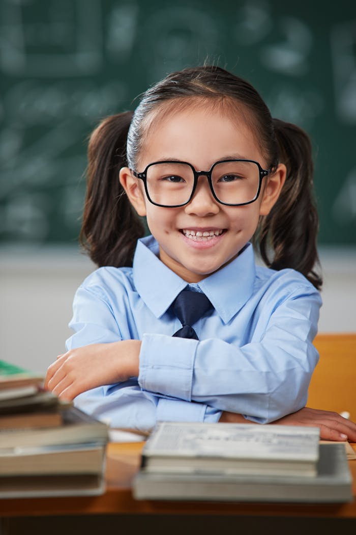 gallery-2 A cheerful elementary schoolgirl in a uniform smiles in front of a blackboard.