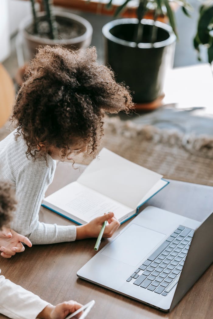 why-choose-us From above of unrecognizable African American schoolgirl with curly hair in casual clothes lying on floor and taking notes in copybook during distance lesson via laptop at home